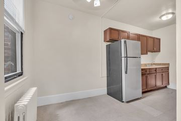 Washington apartment for rent - A kitchen with a refrigerator and brown cabinets.