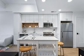 Alexandria apartment for rent - a white kitchen with a white island and a stainless steel refrigerator