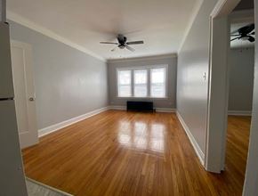 Chicago apartment for rent - A room with wooden floors and a ceiling fan.