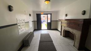 Chicago apartment for rent - A hallway with a fireplace on the right and a door at the end.