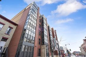 Washington apartment for rent - A tall red brick building with many windows is in the middle of a city street.