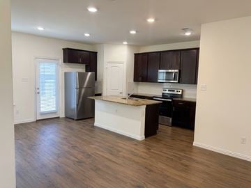 Dallas apartment for rent - A kitchen with a refrigerator, microwave, and oven.