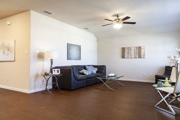 Dallas apartment for rent - A living room with a black couch and a ceiling fan.
