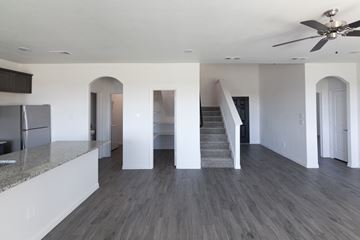 Dallas apartment for rent - A spacious kitchen with a refrigerator and a staircase leading to the upper floor.
