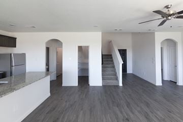 Dallas apartment for rent - A spacious kitchen with a refrigerator and a staircase leading to the upper floor.