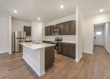 Farmersville apartment for rent - A kitchen with brown cabinets and a white island.