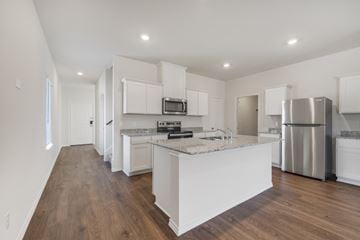 Waxahachie apartment for rent - A kitchen with white cabinets and a wooden floor.