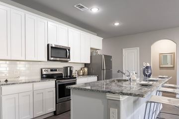 Waxahachie apartment for rent - A modern kitchen with white cabinets and a granite countertop.