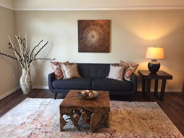 Virginia Beach apartment for rent - A living room with a blue couch, a wooden coffee table, and a painting on the wall.