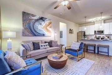 Knoxville apartment for rent - A living room with a large painting on the wall and a kitchen area in the background.