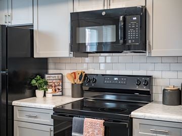 Columbus apartment for rent - A black microwave is mounted above a black stove in a kitchen.
