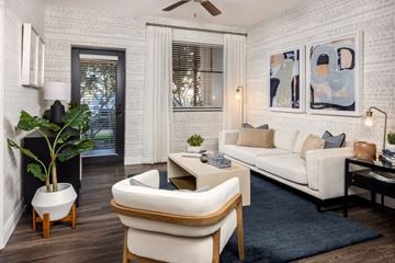 West Palm Beach apartment for rent - A living room with a white couch, a chair, a potted plant, and a painting on the wall.