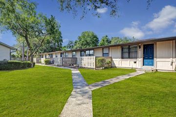Orange City apartment for rent - A long building with a blue door is surrounded by a green lawn.