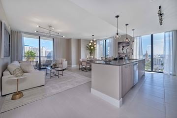Miami apartment for rent - A modern living room with a large white sofa and a kitchen area with a bar.