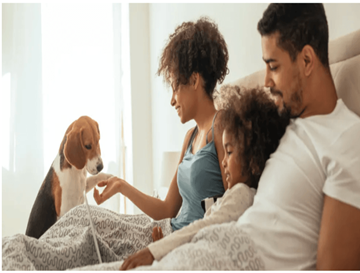 Palm Springs apartment for rent - A family of three is sitting on a bed with a dog.