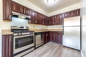 Ewing Township apartment for rent - A kitchen with brown cabinets and a stainless steel refrigerator.