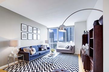 New Rochelle apartment for rent - A living room with a blue couch and a black and white rug.