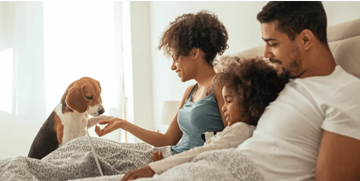Cutler Bay apartment for rent - A family of three is sitting on a bed with a dog.