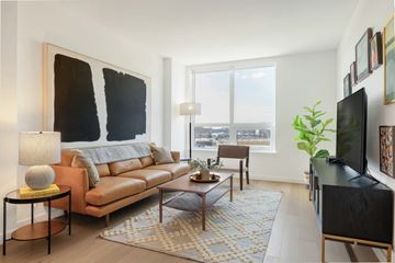 Reston apartment for rent - A living room with a brown leather couch, a coffee table, a lamp, and a large painting on the wall.