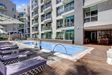 Long Beach apartment for rent - A pool area with lounge chairs and a building in the background.