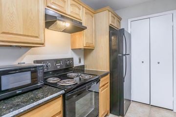 Orlando apartment for rent - A kitchen with a black stove top oven and a black microwave.