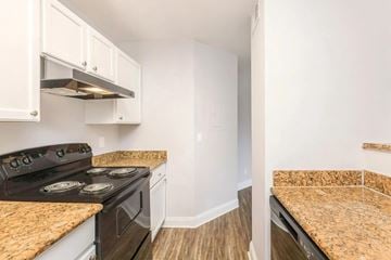 Orlando apartment for rent - A kitchen with a black stove top oven and white cabinets.