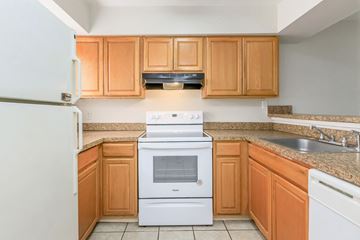 Winter Park apartment for rent - A white oven and microwave in a kitchen with wooden cabinets.