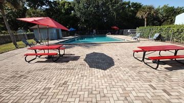 Lakeland apartment for rent - A pool surrounded by red umbrellas and benches.