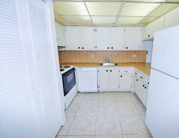 Pompano Beach apartment for rent - A kitchen with white cabinets and a white refrigerator.
