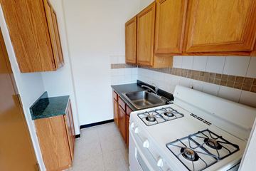 Chicago apartment for rent - A kitchen with a white stove and wooden cabinets.