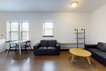 Chicago apartment for rent - A black couch sits in a living room with a wooden coffee table in front of it.