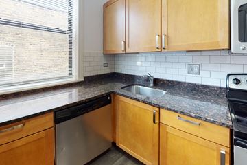 Chicago apartment for rent - A kitchen with wooden cabinets and a black dishwasher.