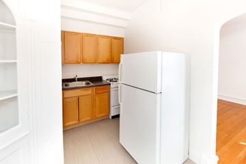 Chicago apartment for rent - A white refrigerator stands in a kitchen with wooden cabinets.