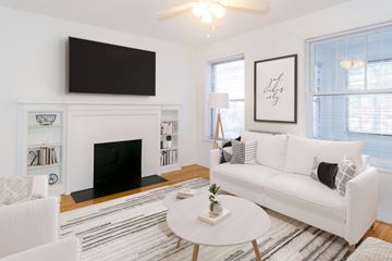 Chicago apartment for rent - A living room with a white couch, a fireplace, and a television mounted above it.