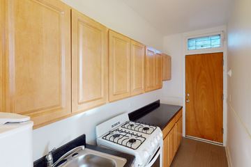 Chicago apartment for rent - A kitchen with wooden cabinets and a white stove top oven.