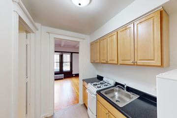 Chicago apartment for rent - A kitchen with wooden cabinets and a black countertop.