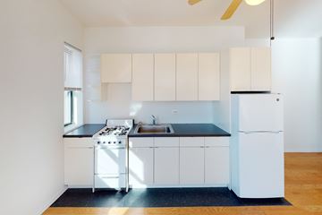 Chicago apartment for rent - A white kitchen with a black counter top and a white fridge.