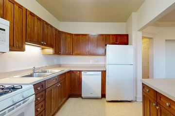Chicago apartment for rent - A kitchen with white appliances and wooden cabinets.