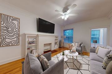 Chicago apartment for rent - A living room with a grey couch and a television mounted on the wall.
