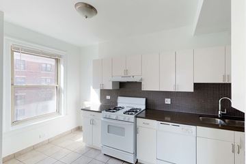 Chicago apartment for rent - A kitchen with white cabinets and a black countertop.