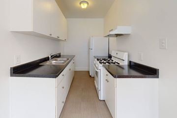 Chicago apartment for rent - A kitchen with white cabinets and black countertops.