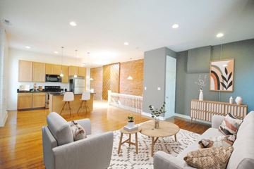 St. Louis apartment for rent - A modern living room with a grey sofa, a wooden coffee table, and a kitchen area in the background.