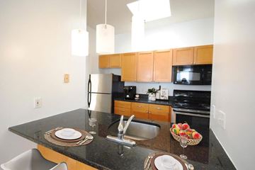 St. Louis apartment for rent - A kitchen with a black granite countertop and wooden cabinets.