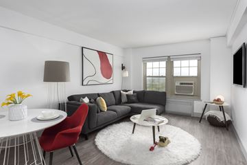 St. Louis apartment for rent - A modern living room with a grey sofa, a red chair, a white coffee table, and a large abstract painting on the wall.