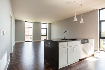 Kansas City apartment for rent - A kitchen with white cabinets and a black countertop.