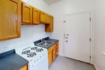 Chicago apartment for rent - A kitchen with a white stove top oven and wooden cabinets.