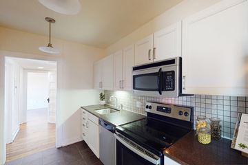 Kansas City apartment for rent - A modern kitchen with a black stove top oven and white cabinets.