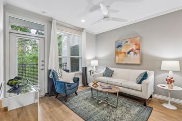Spring apartment for rent - A living room with a blue chair, a white couch, and a painting on the wall.