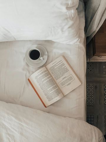 Pasadena apartment for rent - A book is open and lying on a bed with a cup of coffee beside it.