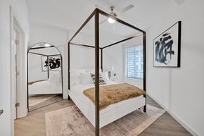 Tampa apartment for rent - A bedroom with a four poster bed and a mirrored wall.